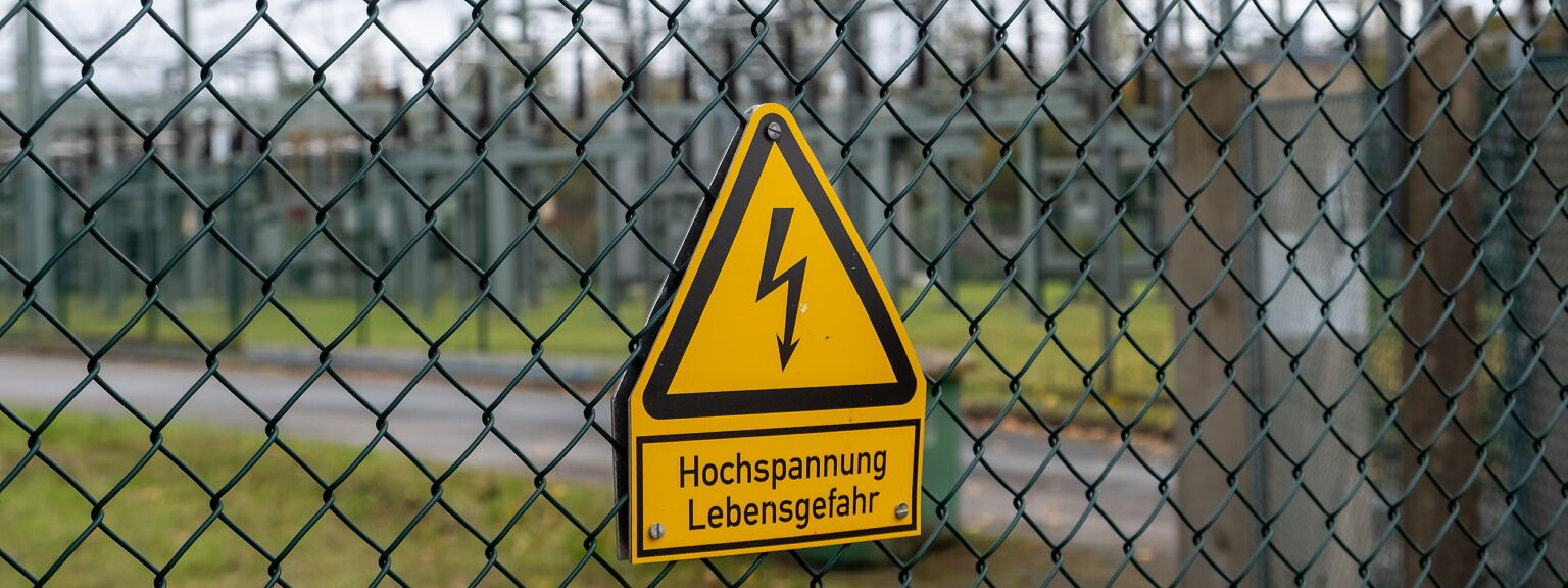 Ein Warnschild mit Blitz, Hochspannung Lebensgefahr am Zaun eines Umspannwerkes