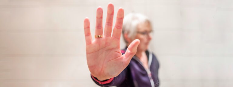 Eine Frau presst eine Hand an eine Glasscheibe.