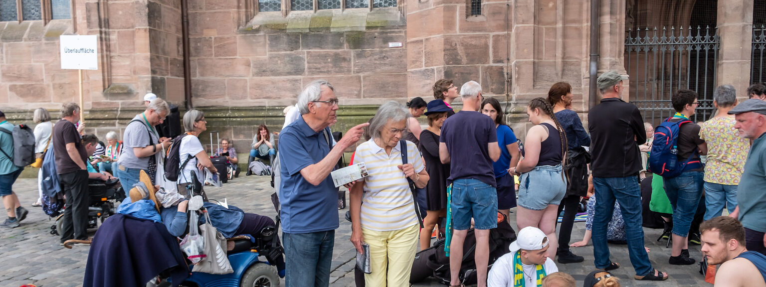 Ein Spiegelbild unserer Gesellschaft - Eine Gruppe Menschen vor der Lorenzkirche am Kirchentag in Nürnberg im Juni 2023